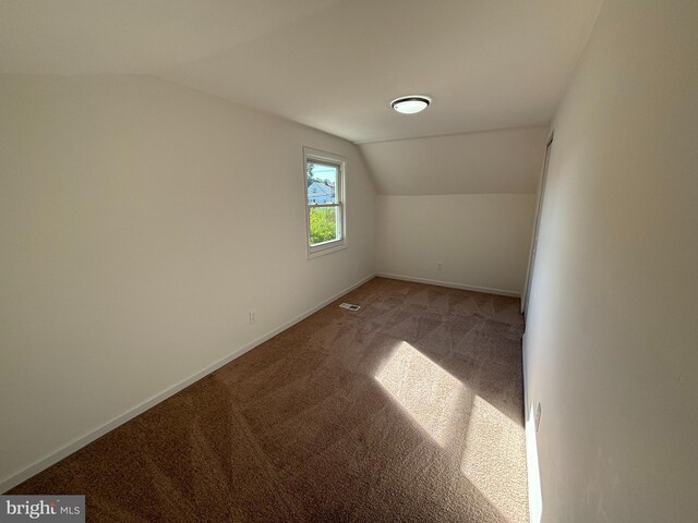 spare room featuring carpet floors and lofted ceiling