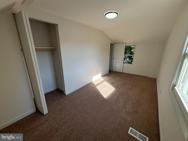 unfurnished bedroom with visible vents, carpet flooring, baseboards, and lofted ceiling