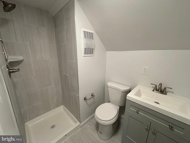 full bath with visible vents, toilet, a tile shower, lofted ceiling, and vanity