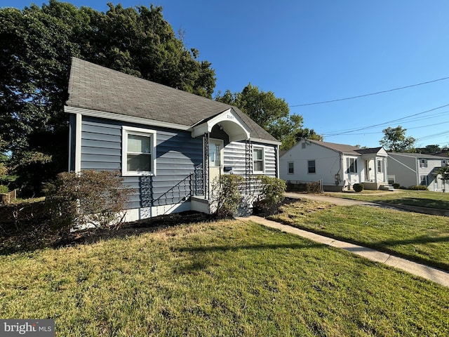 view of front of property featuring a front yard and roof with shingles