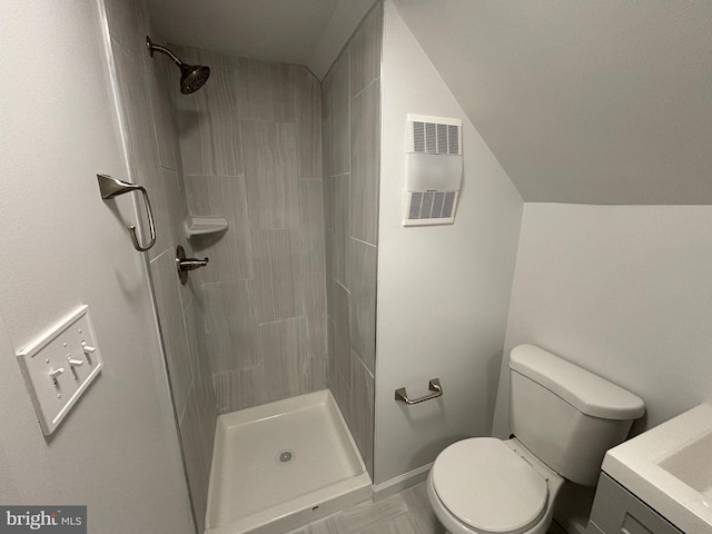 full bathroom featuring vanity, visible vents, lofted ceiling, a tile shower, and toilet