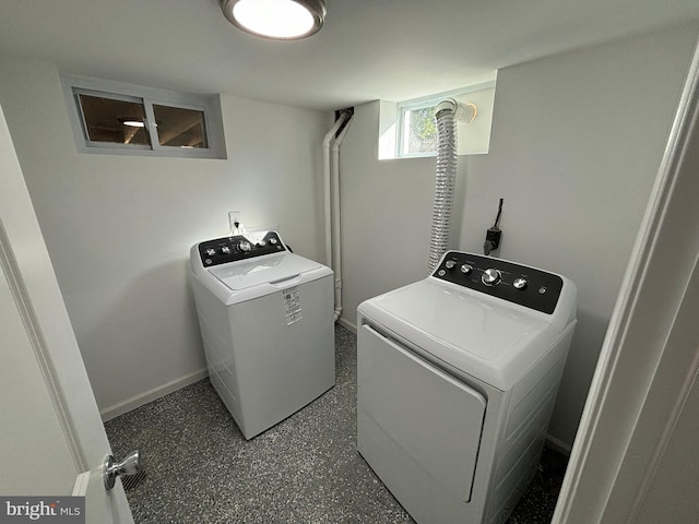 clothes washing area featuring separate washer and dryer and baseboards