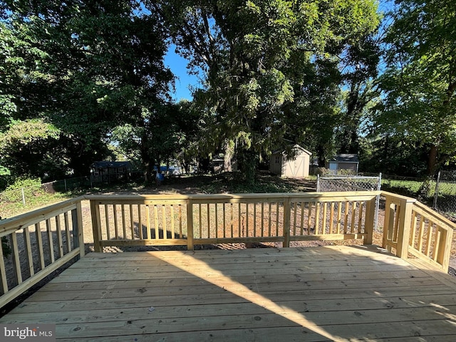 wooden deck featuring an outbuilding, a storage unit, and fence