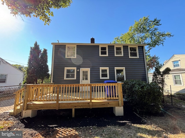 rear view of property featuring a deck, fence, and a chimney