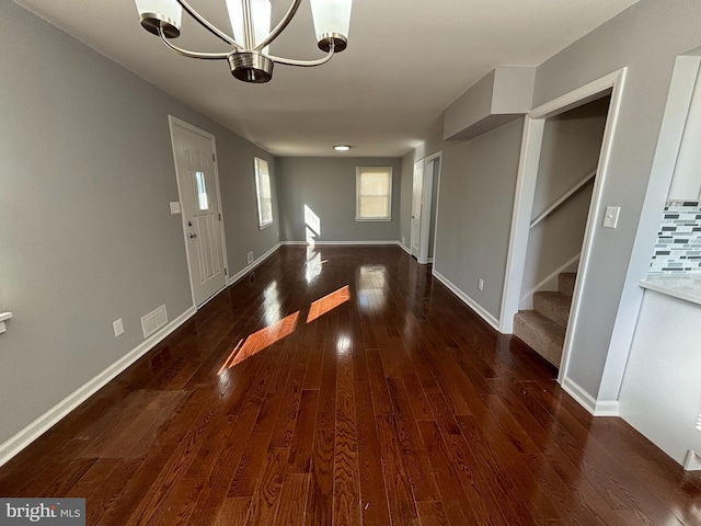 foyer entrance with an inviting chandelier and dark hardwood / wood-style floors