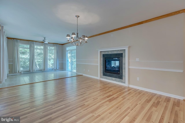 unfurnished living room featuring ceiling fan with notable chandelier, light wood-type flooring, crown molding, and a tile fireplace