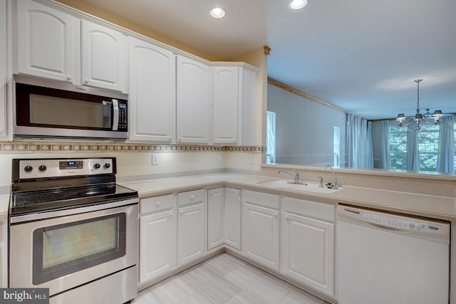 kitchen featuring a notable chandelier, sink, stainless steel appliances, hanging light fixtures, and white cabinetry