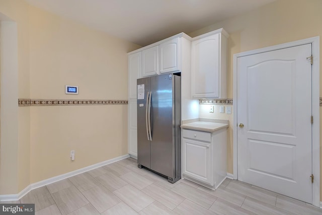 kitchen featuring stainless steel refrigerator and white cabinetry