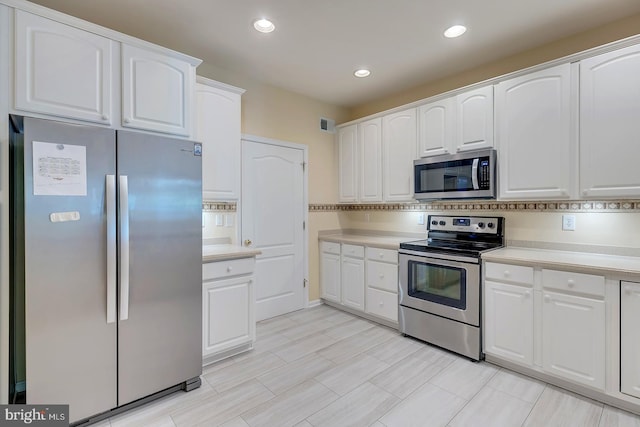 kitchen with appliances with stainless steel finishes, backsplash, and white cabinetry