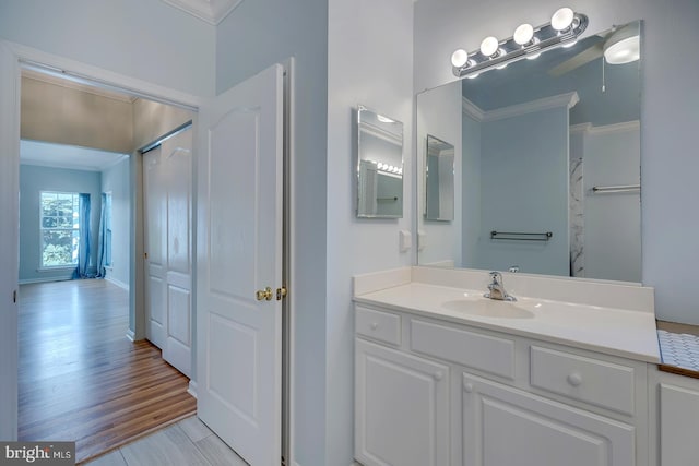 bathroom with crown molding, hardwood / wood-style flooring, and vanity