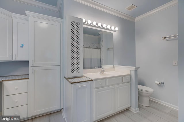 bathroom with ornamental molding, vanity, and toilet