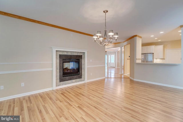 unfurnished living room featuring a fireplace, ornamental molding, a chandelier, and light hardwood / wood-style flooring