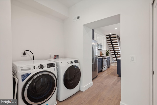 laundry area with separate washer and dryer and light hardwood / wood-style floors