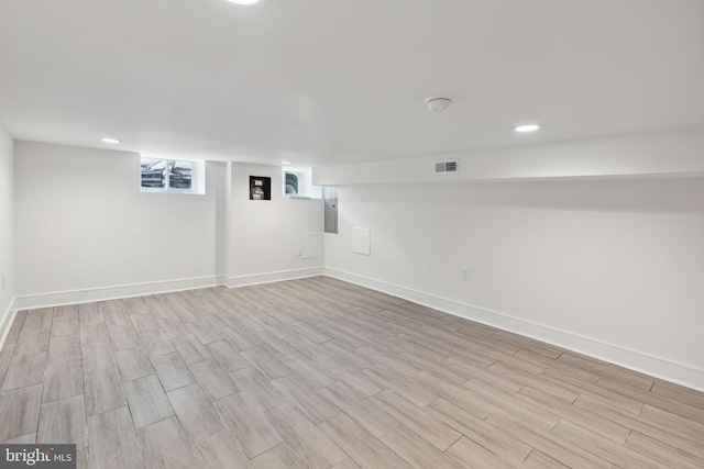 basement with electric panel and light hardwood / wood-style flooring