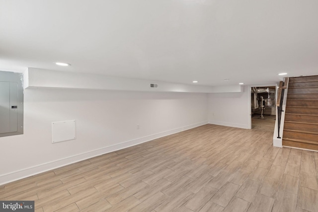 basement with electric panel and light hardwood / wood-style floors