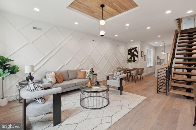 living room featuring light wood-type flooring and a raised ceiling