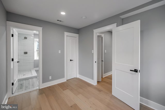 unfurnished bedroom featuring light wood-type flooring and ensuite bath