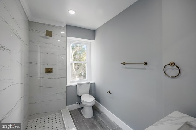 bathroom featuring tiled shower and toilet