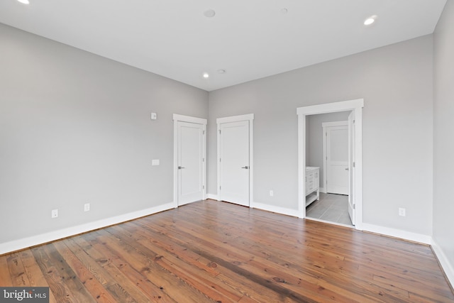 unfurnished bedroom featuring wood-type flooring and ensuite bathroom