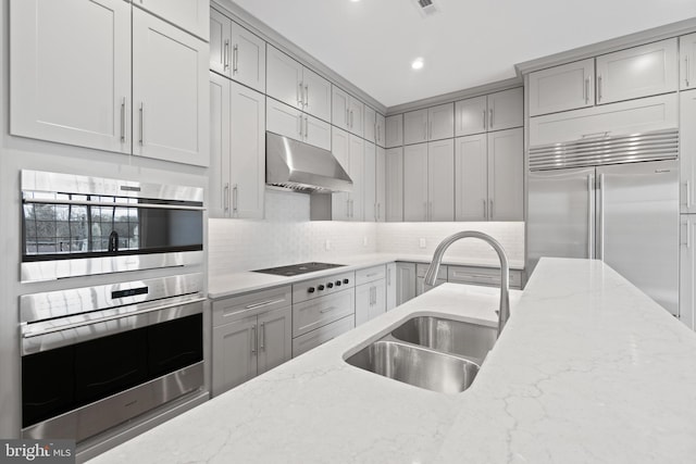 kitchen with stainless steel appliances, sink, light stone countertops, and backsplash