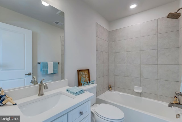 full bathroom with tiled shower / bath combo, vanity, and toilet