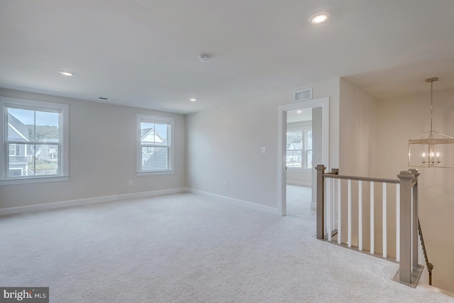 unfurnished room with light carpet and a notable chandelier