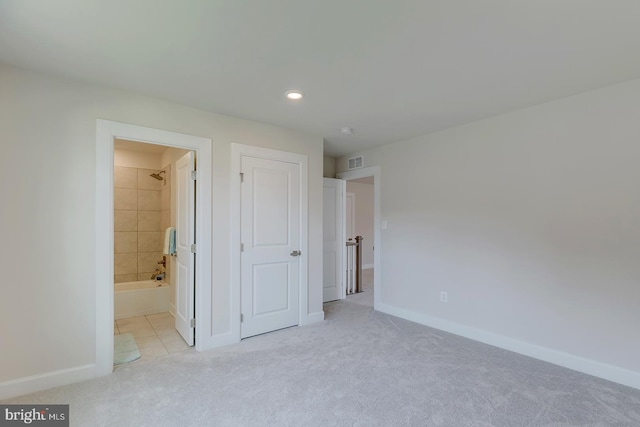 unfurnished bedroom featuring light carpet and ensuite bathroom