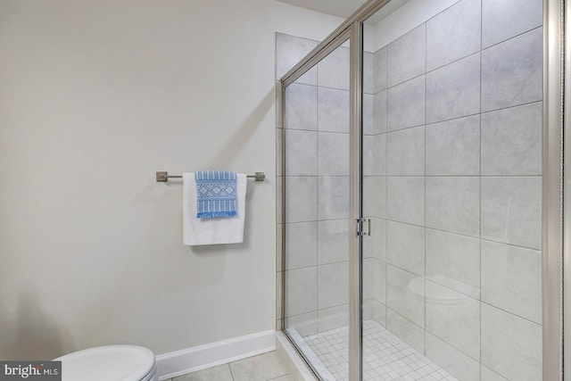 bathroom featuring a shower with shower door, toilet, and tile patterned floors