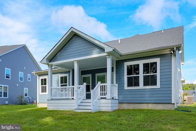 view of front of property featuring cooling unit, a front lawn, and covered porch