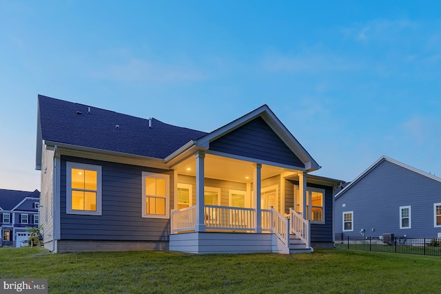 rear view of property featuring a lawn and covered porch