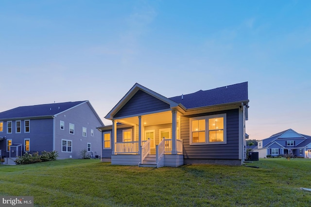 view of front of property featuring cooling unit, a yard, and a porch