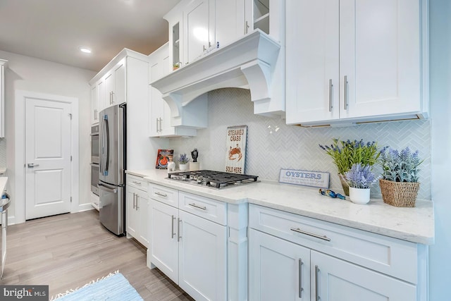 kitchen with light stone countertops, appliances with stainless steel finishes, light hardwood / wood-style floors, and white cabinetry