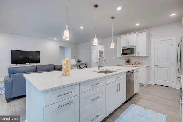 kitchen featuring pendant lighting, white cabinets, sink, a center island with sink, and appliances with stainless steel finishes