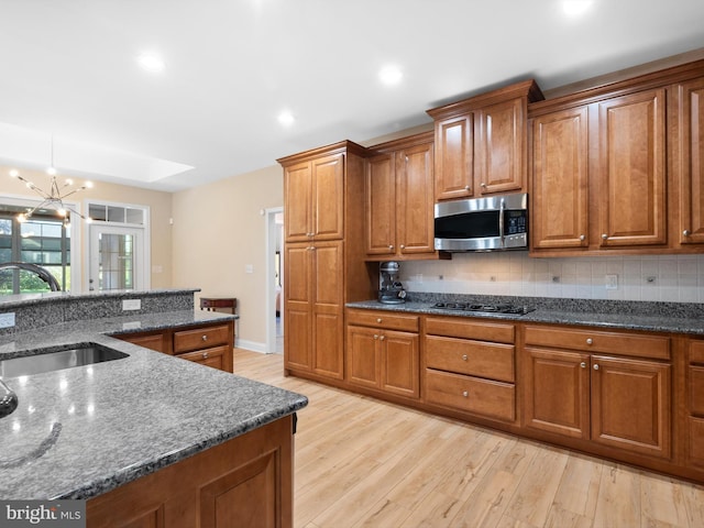 kitchen with stainless steel microwave, brown cabinets, light wood-style flooring, and a sink