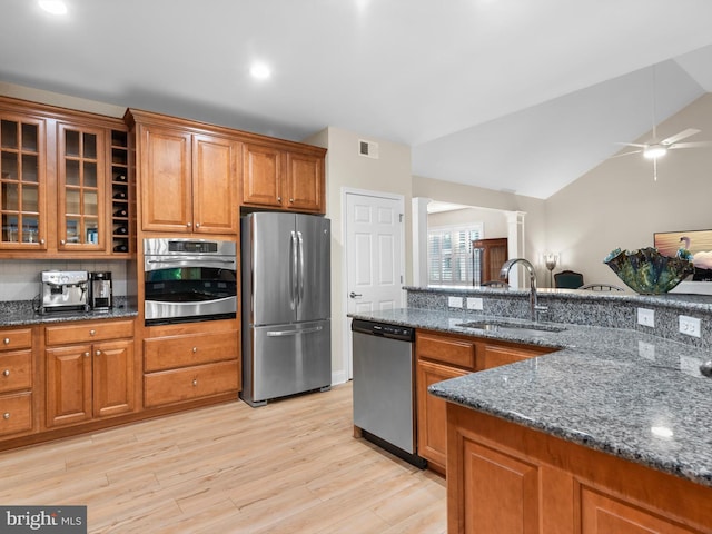 kitchen featuring visible vents, light wood-style flooring, a sink, stainless steel appliances, and brown cabinets