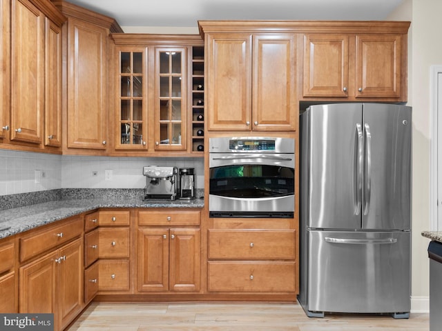 kitchen with stone counters, brown cabinets, and appliances with stainless steel finishes