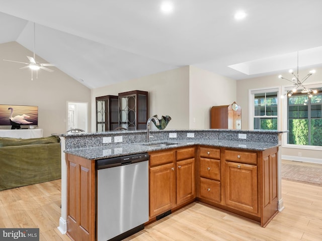 kitchen featuring open floor plan, dishwasher, light wood-type flooring, dark stone countertops, and a sink