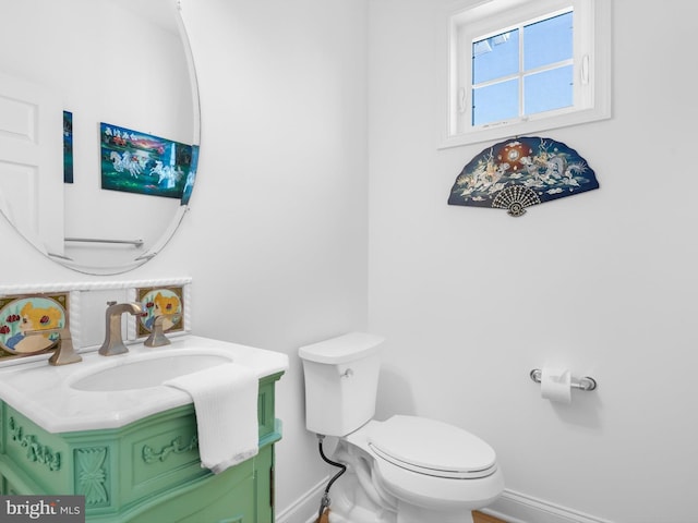 half bath with vanity, toilet, and baseboards