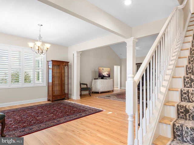 foyer featuring wood finished floors, stairs, baseboards, and decorative columns