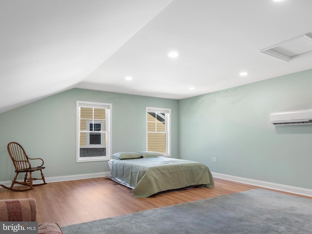 bedroom with vaulted ceiling, a wall mounted air conditioner, baseboards, and wood finished floors