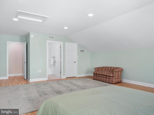 bedroom with visible vents, baseboards, wood finished floors, and vaulted ceiling