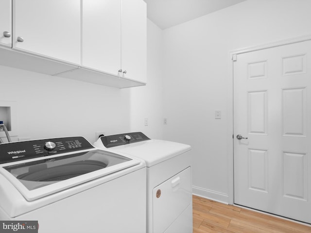 laundry room featuring washer and dryer, baseboards, cabinet space, and light wood-style flooring