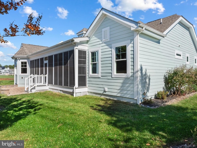 back of property with a yard, roof with shingles, and a sunroom