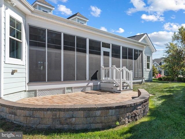 rear view of house featuring a lawn and a sunroom