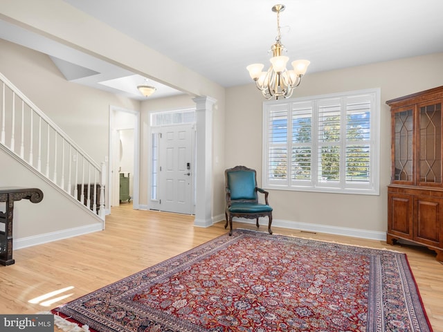 foyer entrance with stairway, a notable chandelier, wood finished floors, and baseboards