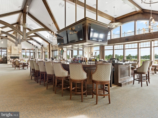 carpeted dining space with beamed ceiling, a large fireplace, high vaulted ceiling, and a community bar