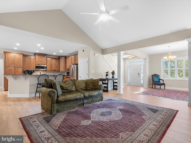 living area with baseboards, light wood finished floors, high vaulted ceiling, decorative columns, and ceiling fan with notable chandelier