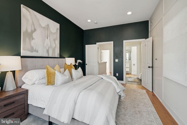 bedroom featuring ensuite bath and light hardwood / wood-style flooring