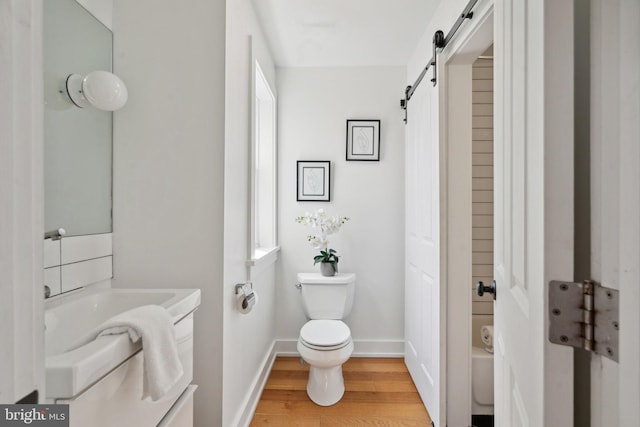 bathroom with wood-type flooring, toilet, a bathtub, and vanity