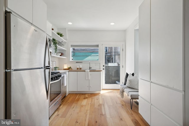 kitchen with light hardwood / wood-style flooring, sink, stainless steel appliances, and white cabinets